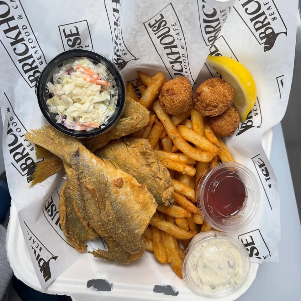Fried fish, french fries, hushpuppies, coleslaw, and sauces in a Brickhouse Seafood Cafe container.