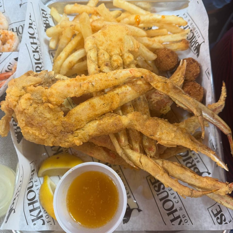 Fried soft-shell crab and french fries with hush puppies, lemon wedges, and dipping sauce.